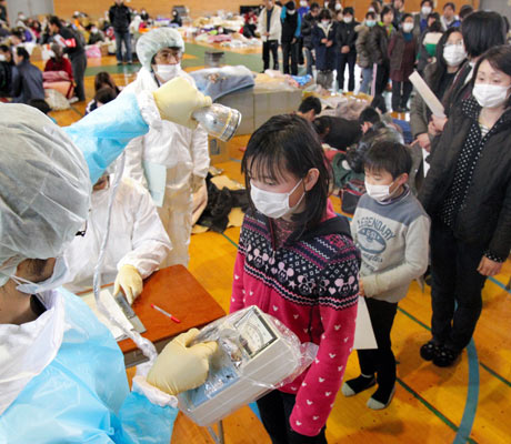 Japanese medical personnel check a child for radiation exposure